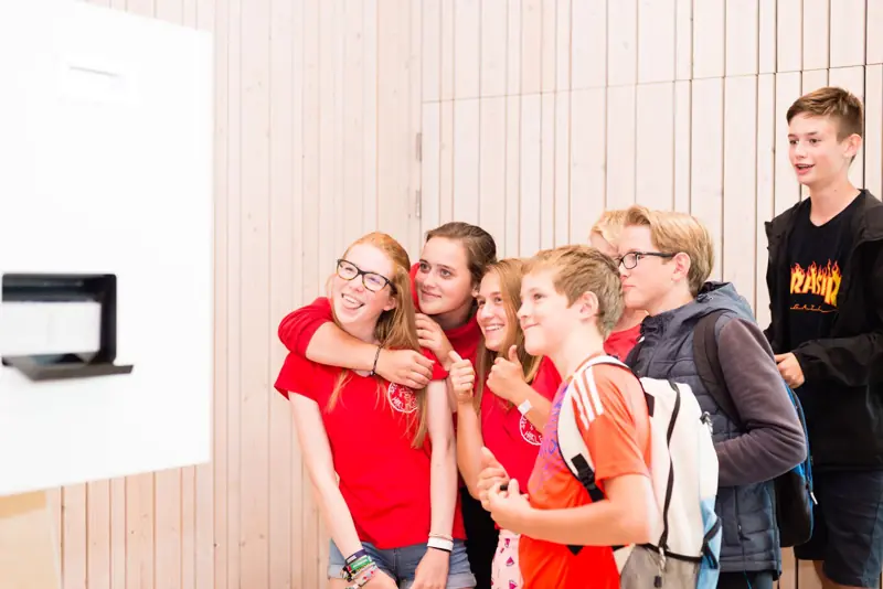 Groep jongeren lacht naar de photobooth